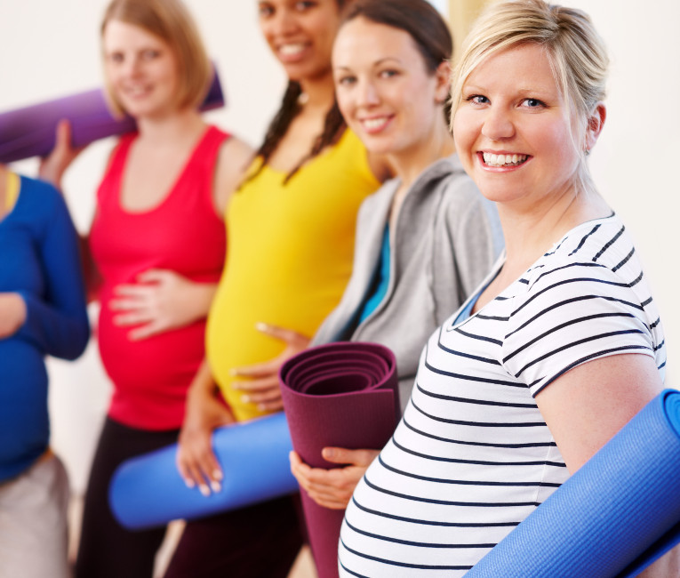 Pregnant ladies with their yoga mats getting ready for a pregnancy for yoga class